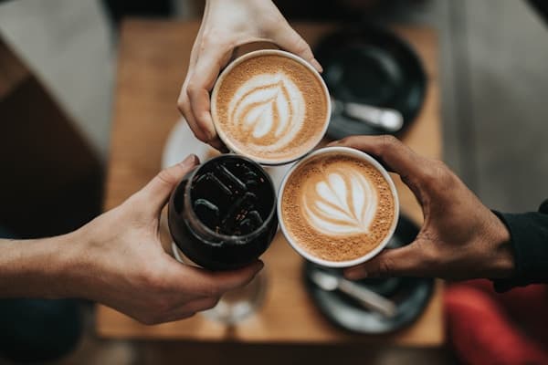 coffee shop owner smiling behind counter with coffee equipment and warm lighting